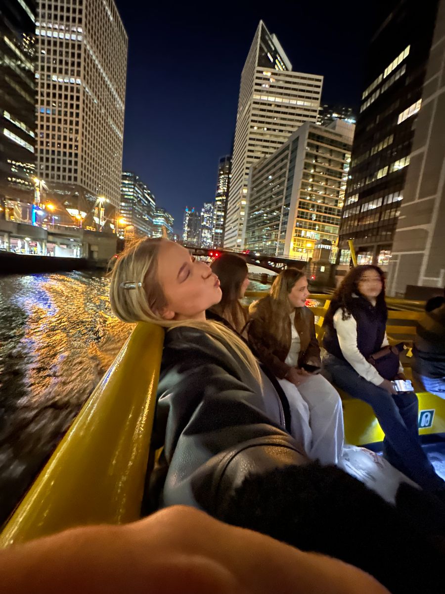 Selina with friends on a boat between skyscrapers at night